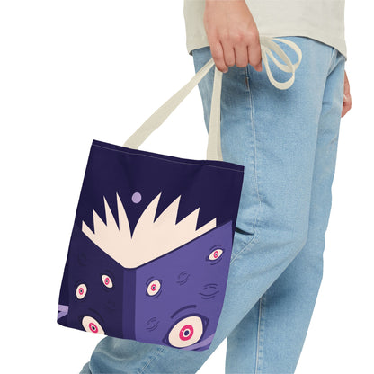 A person wearing light blue jeans and a cream t-shirt holds a canvas tote bag. The bag is dark purple with a cartoon monster face design featuring multiple eyes and a cream-colored mouth.