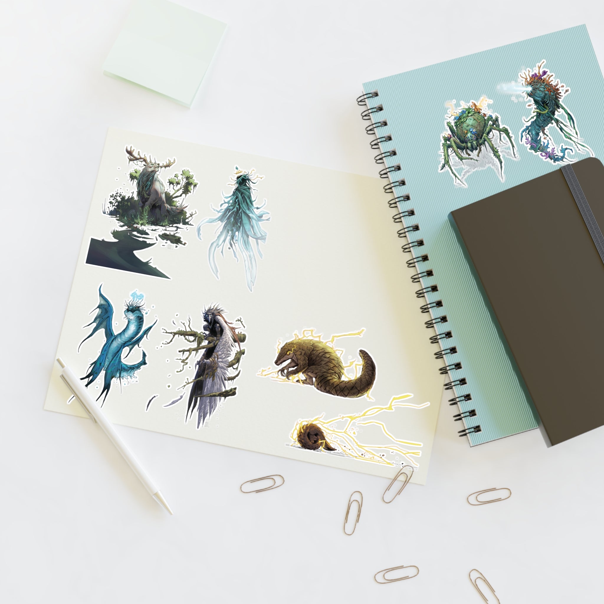 Sticker sheet with fantasy creature designs on a wooden desk.